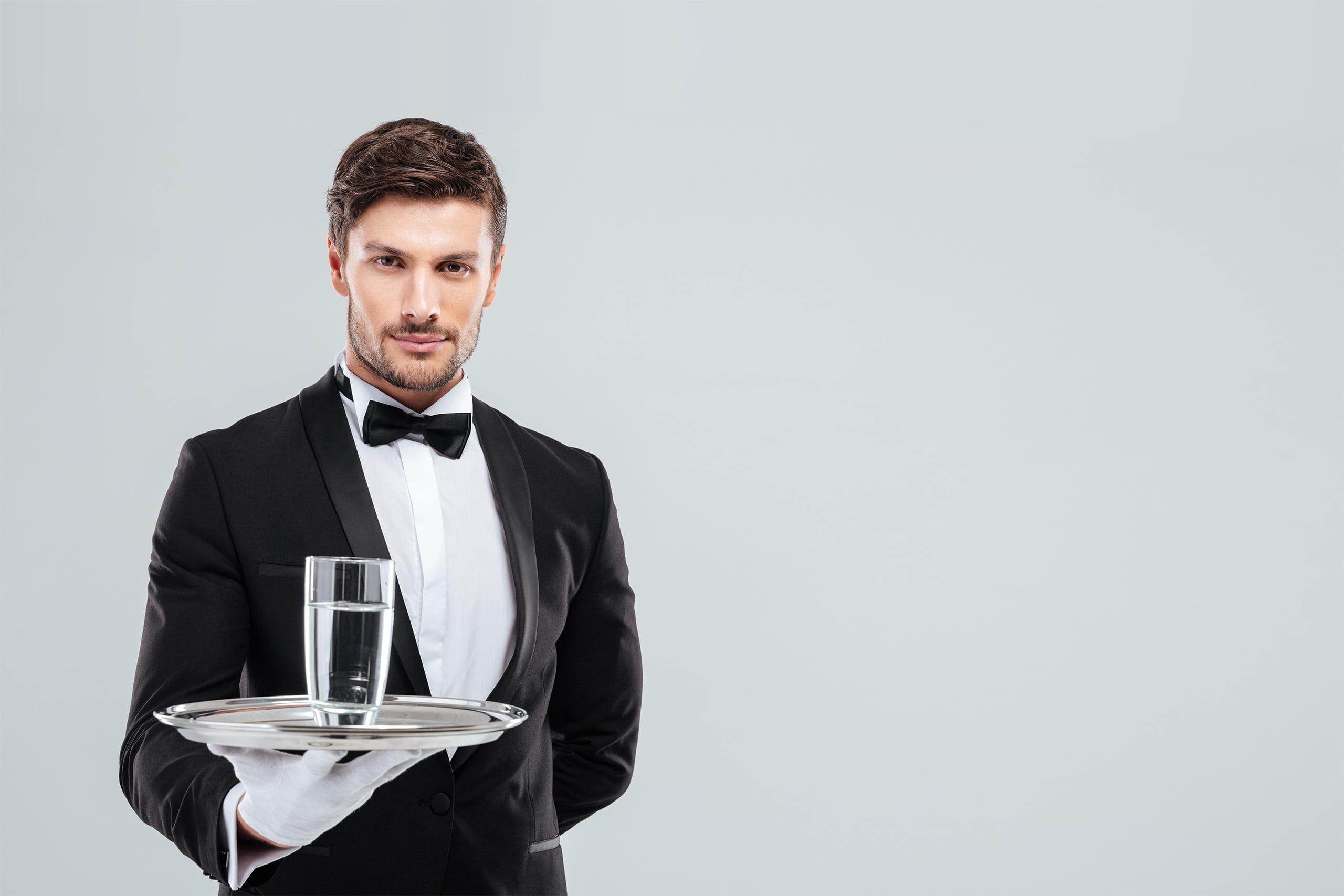 Ein Butler serviert ein Glas Wasser